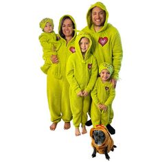 three adults and two children in green onesuits with a dog standing next to them