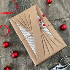 an open brown envelope with red ornaments and scissors on the table next to it,