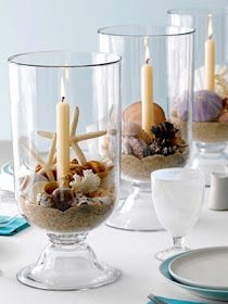 there are candles that are in the glass vases with shells and seashells