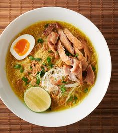 a white bowl filled with noodles, meat and an egg