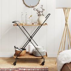 a table with plates, cups and vases on it next to a wall mounted mirror