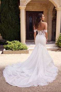 a woman in a white wedding dress is looking off into the distance while standing outside