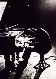 a man sitting at a piano with his head on the piano's back legs