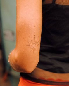 a person with a sun tattoo on their left arm and right arm behind her back