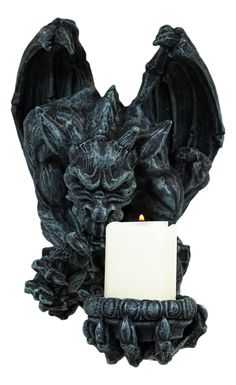 a candle is lit in front of a black dragon statue with its wings spread out