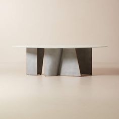 a white table with three metal sections on it's top and bottom, in front of a beige wall