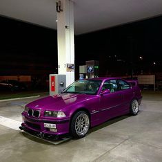 a purple car is parked at a gas station