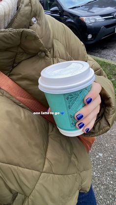 a woman holding a cup of coffee in her right hand and wearing a brown jacket