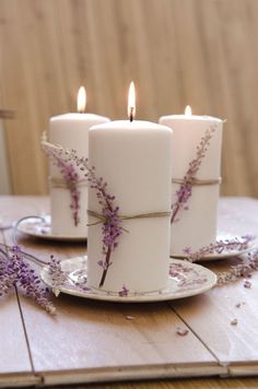 three white candles with purple flowers on them