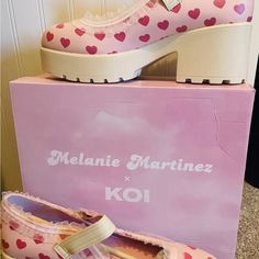 a pair of pink shoes sitting on top of a box with hearts painted on it