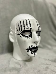 a white mask with black paint on it