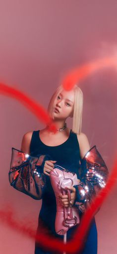 a woman with blonde hair holding a pink object in her hands and looking at the camera