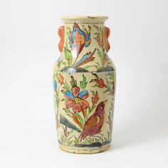 a ceramic vase with birds and flowers painted on the front, sitting against a white background