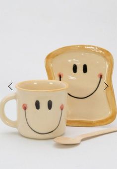 two pieces of toast with faces painted on them, one has a spoon in front of it