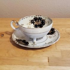 an antique tea cup and saucer on a wooden table with gold trimmings