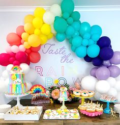 a rainbow themed birthday party with balloons and desserts