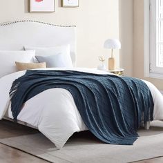 a bed with white sheets and blue blanket