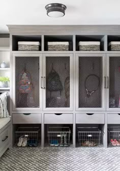 a room filled with lots of white cabinets and baskets on top of each cabinet in front of a couch