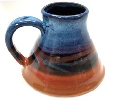 a blue and brown vase sitting on top of a white table