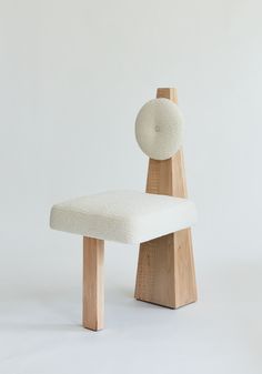 a white chair sitting on top of a wooden block next to a ball shaped object