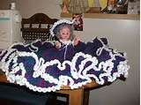 a crocheted table cloth with a doll on it sitting on a wooden table