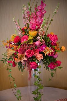 a vase filled with lots of different colored flowers on top of a white table cloth