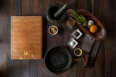 a wooden table topped with lots of different types of cooking utensils and food