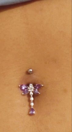 a close up of a person with a piercing on their stomach and an object in the shape of a cross