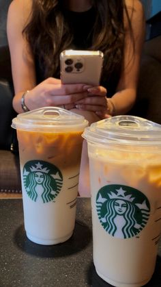 two cups of coffee sitting on top of a table next to each other with drinks in them