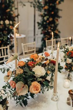 the table is set with candles, flowers and greenery for an elegant wedding reception