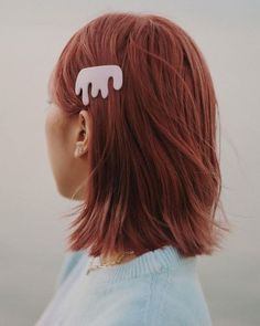 a woman with red hair wearing a pair of ear clips in the shape of an elephant