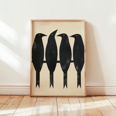 three black birds sitting on top of a wooden floor next to a white wall and hardwood floor