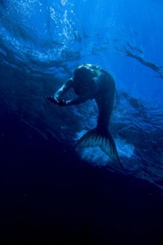 a man is swimming in the ocean with his hands on his face and arms outstretched