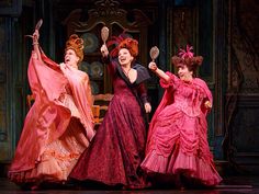 three women in red dresses are on stage and one woman is holding a spatula