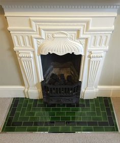 a white fireplace with green tiles and a black fire place in the middle of it