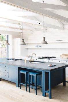 a kitchen with two blue stools and an island in the middle of the room