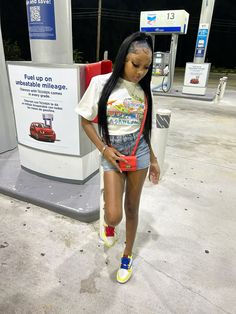 a woman is standing in front of a gas station with her hand on her hip