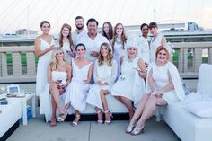 a group of people dressed in white posing for a photo on the roof of a building