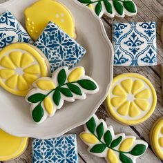 decorated cookies with lemons and leaves on a plate next to blue and white tiles