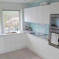 a kitchen with white cabinets and stainless steel appliance in the center, near a window