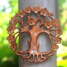 a metal tree with flowers on it's face is hanging from a wooden pole