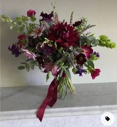 a bouquet of flowers sitting on top of a marble counter next to a white wall