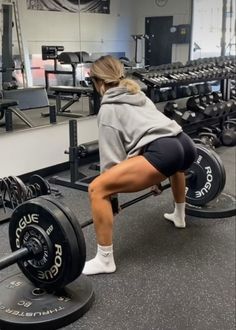 a woman squats on a barbell in a gym