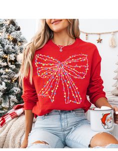 a woman wearing a red sweater with a bow on it and holding a coffee mug