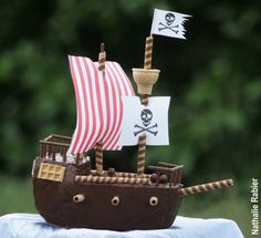 a toy pirate ship is on top of a blue cloth with trees in the background