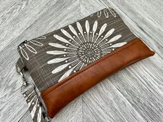 This cute wristlet wallet is the perfect go to alternative to our everyday handbags! It will hold all your necessities including credit cards, ID and your smartphone and your cash. Super functional! This sleek and contemporary wristlet clutch features a heavy weight dark grey/brown and white colored fabric and a tan vegan leather base with a detachable strap. The well organized interior is a solid grey fabric that has 4 credit card slots with a slip pocket behind it for cash. Opposite the credit cards is an interior slip pocket with two lipstick/chapstick pockets on either side.  The approximate dimensions are: 8 1/2" long 5 1/2" tall 10" loop for wrist strap The cell phone in the pictures measures approx. 6 3/4" x 3 1/2" with an otterbox case Please note there may be some slight variation Brown Rectangular Wristlet With Cell Phone Pocket, Adjustable Rectangular Wristlet Mobile Phone Bag, Adjustable Rectangular Wristlet For Mobile Phone, Adjustable Wristlet With Cell Phone Pocket For Gifts, Adjustable Rectangular Wristlet With Zipper Pouch, Everyday Handbags, Everyday Handbag, Otter Box, Colored Fabric