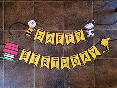 a happy birthday banner on the floor with peanuts and snoopy characters hanging from it