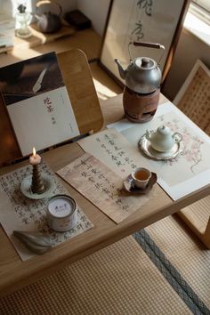 a table with tea cups, candles and pictures on it