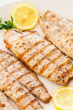 grilled fish with lemons and parsley on a white plate