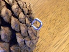 a close up of a pine cone with a ring on it's end, sitting on a wooden table